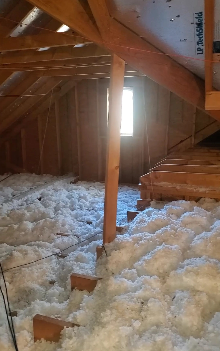 Finished attic with blown-in fiberglass insulation covering the ceiling joists